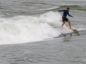 A surfer catches a wave at the Habitat '67 Standing Wave, in Montreal,  July 23, 2015. The city has warned that people who usually surf on the continuous wave or who kayak in that part of the river should avoid doing so during the upcoming construction of a new snow chute in October.