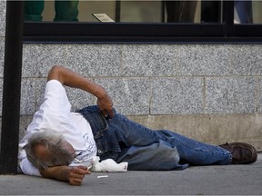 A man lays on the street at the corner of Peel and Ste-Catherine Sts.