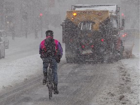 A downtown cyclist follows a snowplow in March 2013.