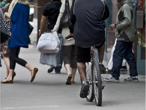 A cyclist rides his bicycle on the sidewalk on Ste- Catherine St. near McGill College Ave.