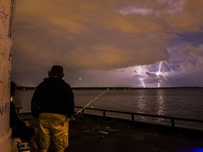 Fishermen in Lachine watch an intense lightning storm July 27, 2015.