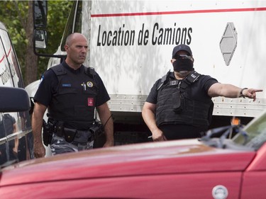 A driver of a truck that arrived to pick up silver from the rear of a tractor trailer in the Pointe-Claire area of Montreal Thursday, September 10, 2015 gives a warning to a journalist as a police officer walks by. Police arrested five men Wednesday evening in Montreal in connection with the theft of a cargo container last week that was carrying an estimated $10 million in silver bars.