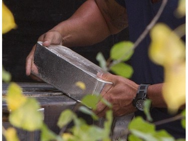 A Montreal police investigator unloads a silver brick from the rear of a tractor trailer in the Pointe-Claire area of Montreal, Thursday, September 10, 2015.