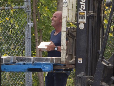 A Montreal police investigator picks up a silver brick from a pallet in front of him after they were recovered from the rear of a tractor trailer in the Pointe-Claire area of Montreal, Thursday, September 10, 2015.
