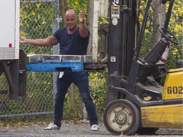 A Montreal police investigator prepares to pick up a silver brick from a pallet after they were recovered  from the rear of a tractor trailer in the Pointe-Claire area of Montreal, Thursday, September 10, 2015.