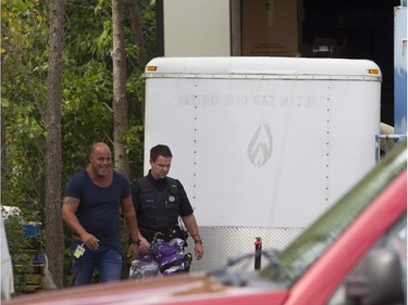 A Montreal police investigator (left) smiles after a tractor trailer (upper right) was opened to reveal stolen silver bricks in the Pointe-Claire area of Montreal, Thursday, September 10, 2015.