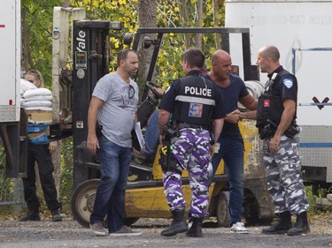 Montreal police investigators and police officers shake hands after silver bricks were recovered from the rear of a tractor trailer in the Pointe-Claire area of Montreal, Thursday, September 10, 2015.