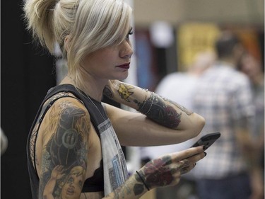 Sophie Liset uses her phone while enjoying the art tattoo show held in Montreal on Friday September 11, 2015. The show at Place Bonaventure goes on through the weekend.