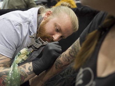 Tatoo artist Dusty Neal puts down his art on Becky Cloonan during art tattoo show in Montreal on Friday September 11, 2015. The show at Place Bonaventure goes on through the weekend.