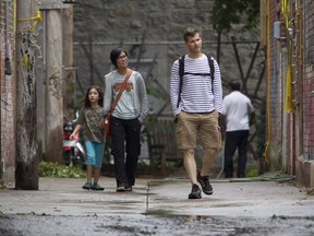 Luc de Montigny, his wife, Dao Nguyen, and their daughter Sen, walk down an alley leading to Napoléon St., between de l'Hôtel-de-ville and Laval Aves. The lane, popular with some residents in the area was cleared by a city crew in Montreal Saturday, Sept. 12, 2015. The lane had been filled with various items, including paintings by local children (some by Sen de Montigny), picnic tables and Muskoka chairs painted bright pink, flower beds growing out of used bathtubs and toilets.