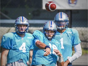 Alouettes quarterbacks Tanner Marsh, left, and Brandon Bridge watch as Jonathan Crompton passes the football during practice in Montreal on Sept. 16, 2015.