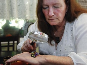 Barbara Blusanovics uses a magnifying glass to inspect jewelry at her home. A master of rummage sales, she counsels wisely: "Don't take home anything you won't enjoy wearing or looking at, no matter how good a deal it might seem."