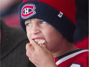 Six-year-old Alexis Sauve keeps his eyes on the game while he devours his cotton candy at the Canadiens' annual open-house practice at Montreal's Bell Centre on Sept. 20, 2015.