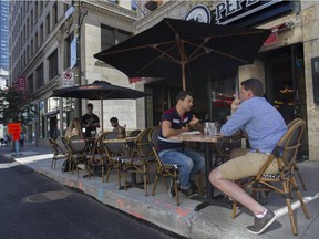 People enjoy the weather on an sidewalk terrace on Peel St., which has partially reopened after summer construction.