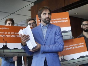 Steven Guilbeault of the environment group Équiterre, middle, holds 90,000 petitions signed by people against the TransCanada pipeline project. Guilbeault and supporters were at the Centre Mont-Royal on Wednesday September 23, 2015 to deliver that message to the federal political parties.