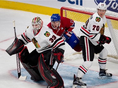 Montreal Canadiens right wing Brendan Gallagher, centre, grimaces as he is hit by Chicago Blackhawks left wing Dennis Rasmussen to clear him from Chicago Blackhawks goalie Scott Darling's crease during NHL pre-season action in Montreal on Friday September 25, 2015.
