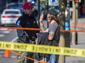 A Montreal police officer speaks to a man at the scene of a stabbing homicide near the corner of St-Denis St. and Viger Ave., near Viger Square, in Montreal on Sunday, September 27, 2015.