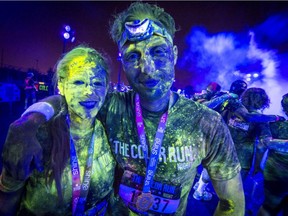 Marie Claude Pineault, left, and Marc-André Patry are covered in coloured powder after finishing the Colour Run on Circuit Gilles Villeneuve at Parc Jean-Drapeau in Montreal on Saturday, September 5, 2015.