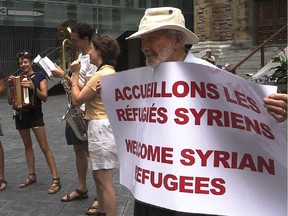 Robert Verrall, right, holds a banner that says "Welcome Syrian refugees" outside St. James United Church in Montreal on Wednesday Sept. 9, 2015.