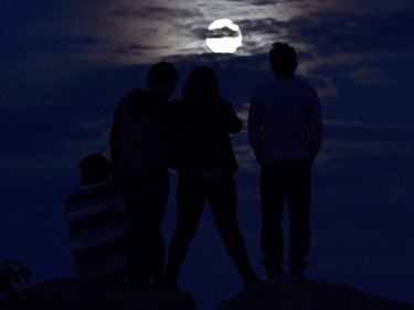 People watch as a so-called supermoon begins to rise in Mississauga, Ontario, Sunday, Sept. 27, 2015.