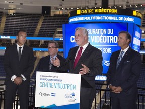 Quebec Premier Philippe Couillard, centre, responds to reporters' questions at the opening ceremony of the Vidéotron Centre on Tuesday, Sept. 8, 2015, in Quebec City. Couillard is flanked by Pierre Dion of Québecor, Regis Labeaume, mayor of Quebec City, and Quebec Labour Minister Sam Hamad. Quebec City is seeking the comeback of the NHL with the inauguration of the new NHL-size arena.