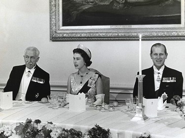 H.M. Queen Elizabeth II, in a gown of white satin, sits between Prince Philip and Govenor-General Vanier at a state dinner at Rideau Hall on Oct. 13, 1964.