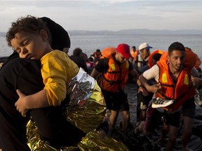 Syrian refugees arrive on a dinghy after crossing from Turkey to Lesbos island, Greece, Wednesday, Sept. 9, 2015. The head of the European Union's executive says 22 of the member states should be forced to accept another 120,000 people in need of international protection who have come toward the continent at high risk through Greece, Italy and Hungary.