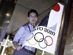 The poster with a logo of Tokyo Olympic Games 2020 is removed from the wall by a worker during an event staged for photographers at the Tokyo Metropolitan Government building in Tokyo Tuesday, Sept. 1, 2015.