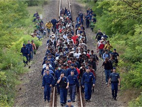 Refugees of different countries accompanied by police officers walk on the railway tracks near Szeged as they broke out from the migrant collection point near Roszke village of the Hungarian-Serbian border on Sept. 8, 2015. Hungary's border with Serbia has become a major crossing point into the European Union, with more than 160,000 entering Hungary so far this year including 2,706 on September 7, 2015 alone, police said.
