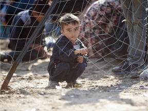 A young boy is pictured as migrants and refugees wait behind a gate for Macedonian police to allow them to cross into Macedonia at the border between Greece and Macedonia near the town of Gevgelija on September 15, 2015. Around 7,600 migrants entered Macedonia in just 12 hours overnight — a record according to a UN official quoted by Macedonia's state news agency on September 11.