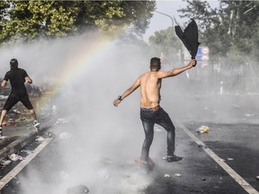 A refugee gestures as Hungarian riot police use water cannon to push back refugees at the Hungarian border with Serbia near the town of Horgos on September 16, 2015. Europe's 20-year passport-free Schengen zone appeared to be a risk of crumbling with Germany boosting border controls on parts of its frontier with France as migrants desperate to find a way around Hungary's border fence began crossing into Croatia. With a string of EU countries tightened frontier controls in the face of the unprecedented human influx, the cherished principle of free movement across borders -- a pillar of the European project -- seemed in grave jeopardy.