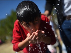A Syrian boy drinks water near the highway on September 17, 2015, on their way to the border between Turkey and Greece. Around 1,000 refugees remained stranded September 16 in the northwestern Turkish city of Edirne, near the Greek border, after being barred by Turkish authorities from continuing their journey to Europe.