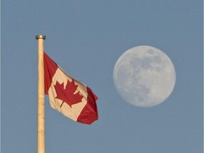A full moon rises up and over the Canadian Flag .