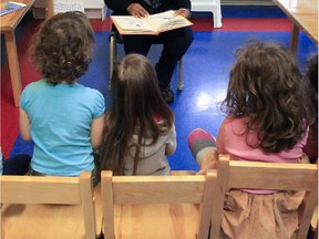 Kids have a story read to them by a child care worker at the Centre de la Petite Enfance Lafonatine in 2013.