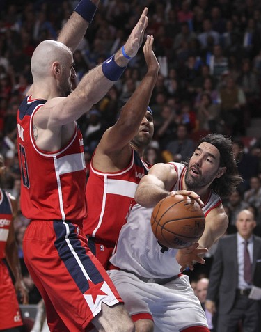 Toronto Raptors Luis Scola passes the ball around Washington Wizards Marcin Gortat, left, and Jared Dudley during National Basketball League pre-season game in Montreal Friday October 23, 2015.