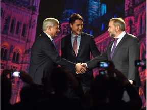 Conservative leader Stephen Harper, left, and NDP leader Tom Mulcair shake hands as Liberal leader Justin Trudeau looks on during their introduction prior to the Globe and Mail hosted leaders' debate in Calgary on September 17, 2015.