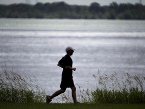 A man jogs along the St. Lawrence River in Montreal on Wednesday, July 9, 2014. The City of Montreal is standing by its plan to dump eight billion litres of untreated wastewater into the St. Lawrence River, saying it remains the best alternative.