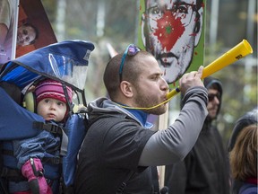 A protester blows a horn as thousands of protesters from a coalition of public sector unions march in the streets of Montreal Saturday, Oct. 3, 2015. The protest included teachers, health workers and labour federation members against the Quebec government's latest contract offers.