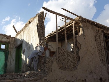 An Afghan boy looks at a damaged house following an earthquake, in Kabul, Oct. 26, 2015.