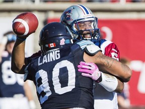Alouettes quarterback Anthony Boone, right, is sacked by Argonauts' Cleyon Laing during second half action in Montreal, Monday, October 12, 2015.