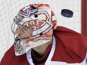 The puck deflects off the glove of Montreal Canadiens' goalie Carey Price and drops behind him before being put in the net by Vancouver Canucks' Jared McCann, not pictured, for a goal during the first period of an NHL hockey game in Vancouver, B.C., on Tuesday, Oct. 27, 2015.