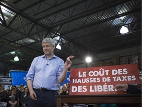 Conservative leader Stephen Harper holds up a $50 bill as he illustrates proposed Liberal tax hikes during a campaign event in Quebec City on Friday, Oct. 16, 2015.