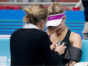 Eugenie Bouchard of Canada reacts as she receives medical attention during her first round match against Andrea Petkovic of Germany in the China Open tennis tournament at the National Tennis Stadium in Beijing, Monday, Oct. 5, 2015.