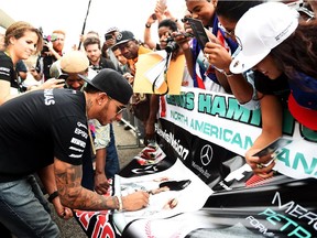 Lewis Hamilton signs autographs for fans in the pit lane ahead of the U.S. Grand Prix at Circuit of The Americas in Austin, Tex.