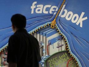 In this June 11, 2014 photo, a man walks past a mural in an office on the Facebook campus in Menlo Park, Calif.