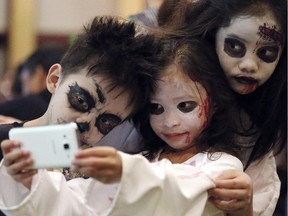 Filipino children, from left, Gabriele Ryan Cortez, Andrea Nicole Baclagan and Chloe Denise Idpan pose for a selfie during a Halloween event in Manila.