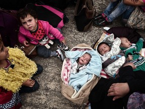 A Syrian family with two-and-a-half-month-old triplets rest after disembarking with other migrants and asylum seekers from two government-chartered ferries at the Greek port of Piraeus, near central Athens, on October 21, 2015.