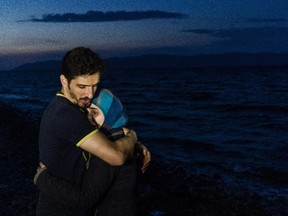 A man hugs his wife on a beach shortly after they arrived with other migrants and refugees by boat on the Greek island of Lesbos after crossing the Aegean sea from Turkey on October 9, 2015. Europe is grappling with its biggest migration challenge since World War II, with the main surge coming from civil war-torn Syria.