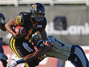 Hamilton Tiger-Cats quarterback Henry Burris, left, is tackled by Winnipeg Blue Bombers linebacker Henoc Muamba during first quarter CFL action in Guelph, Ont., Saturday, July 13, 2013.