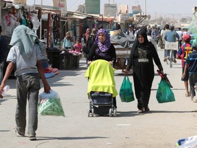 Syrians walk on the main commercial alley dubbed the "Champs Elysée" after Paris' famous avenue by the refugees of the Zaatari refugee camp, in northwestern Jordan, on Sept. 30, 2015. Many refugees are dreaming of a better life in Europe since living conditions in the dusty desert camp are poor with no electricity, little drinking water, and scorching summer temperatures.